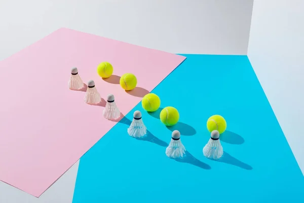 Badminton shuttlecocks and tennis balls on pink and blue — Stock Photo