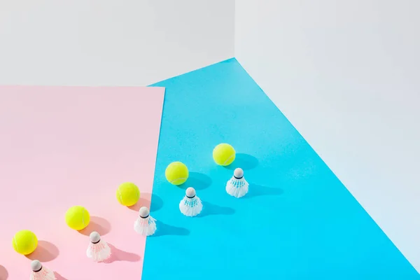 Rows of badminton shuttlecocks and tennis balls on pink and blue — Stock Photo