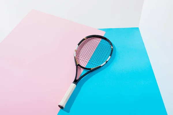 Raqueta de tenis sobre papeles azules y rosados - foto de stock