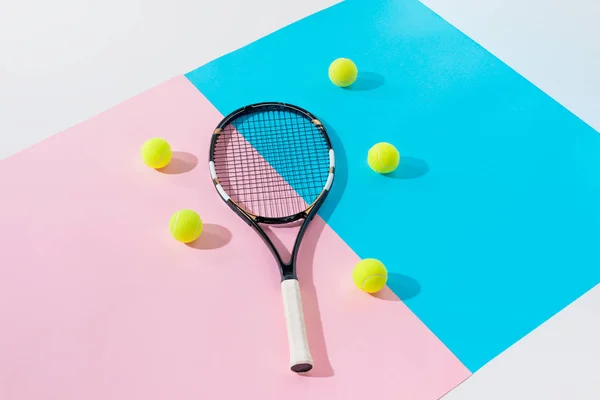 Tennis racket and yellow balls on blue and pink papers — Stock Photo