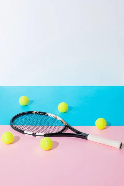 Raqueta de tenis y bolas amarillas sobre papeles azules y rosados con espacio para copias - foto de stock