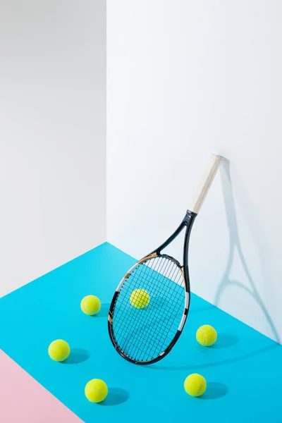 Коло тенісних м'ячів на синьому навколо тенісної ракетки на білій стіні — Stock Photo