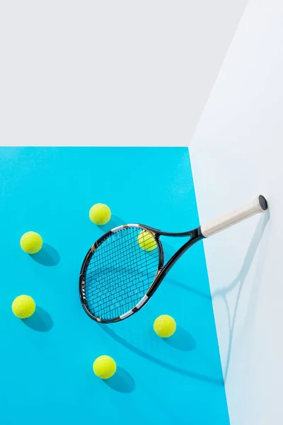 High angle view circle of tennis balls around tennis racket on blue at white wall — Stock Photo