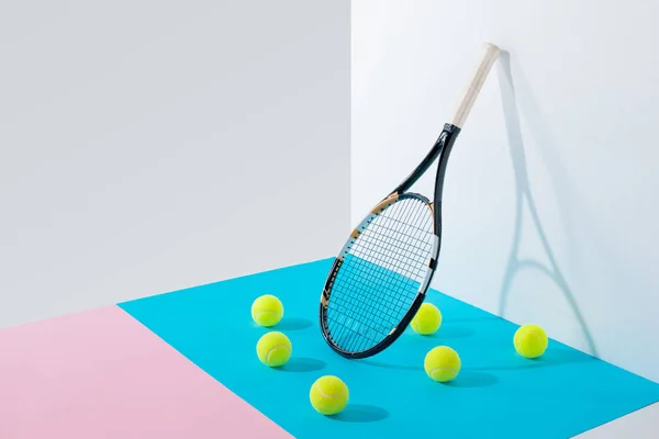 Palline da tennis gialle su carte blu e rosa e racchetta da tennis a parete bianca — Foto stock