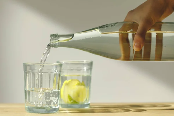 Abgeschnittenes Bild einer Frau, die Wasser in transparentes Glas gießt — Stockfoto