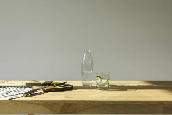 Concombres coupés et eau de désintoxication sur table en bois — Photo de stock