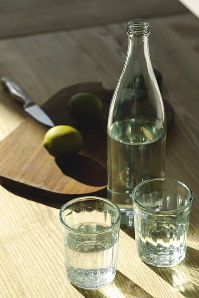 Water and limes for preparing lemonade on table — Stock Photo