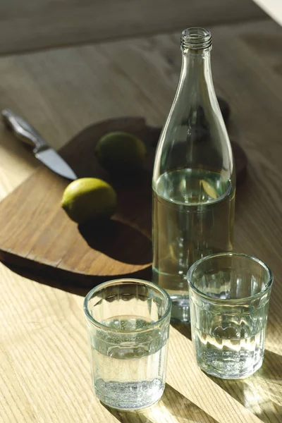 Water and limes for preparing lemonade on table — Stock Photo