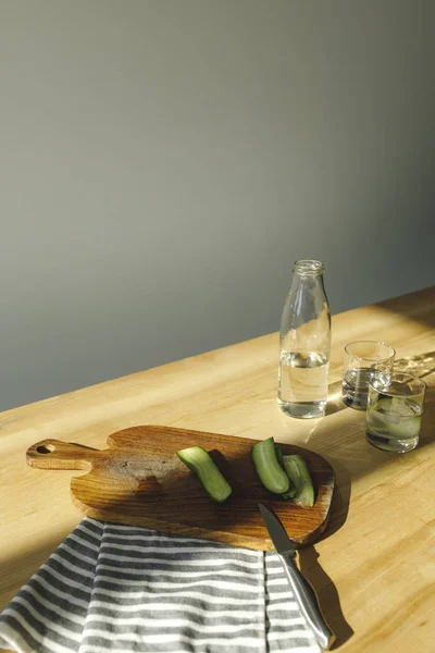 Overhead view of cut cucumbers and antioxidant water on wooden surface — Stock Photo