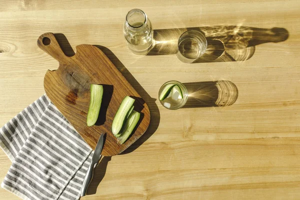 Vista dall'alto di cetrioli tagliati e acqua antiossidante sulla superficie di legno — Foto stock