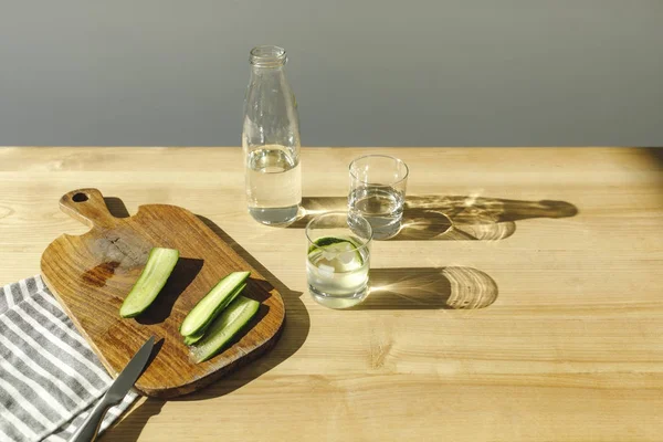 Cut cucumbers on wooden board and mineral water on wooden tabletop — Stock Photo