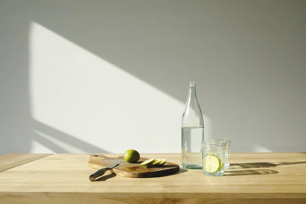 Limas cortadas y agua de desintoxicación en mesa de madera - foto de stock