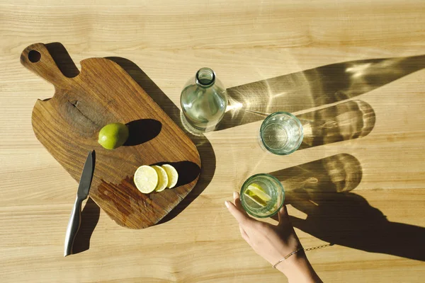 Abgeschnittenes Bild einer Frau, die Glas mit Limonade auf Holztisch legt — Stockfoto