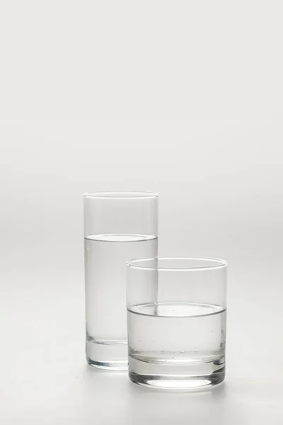 Deux verres différents avec de l'eau calme isolé sur blanc — Photo de stock