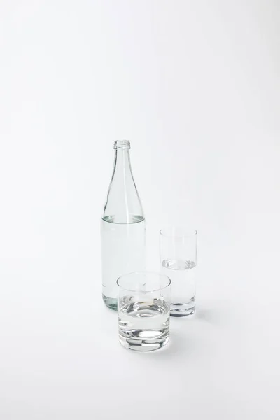 Deux verres différents et une bouteille avec de l'eau calme isolé sur blanc — Photo de stock