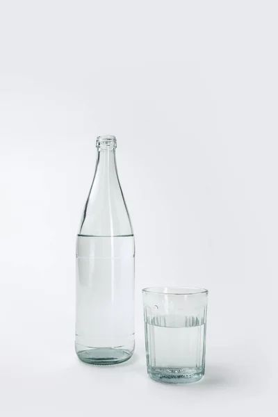 Botella y vidrio con agua mineral aislada en blanco - foto de stock