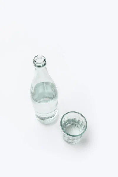 Vue aérienne de la bouteille et du verre avec de l'eau isolée sur blanc — Photo de stock