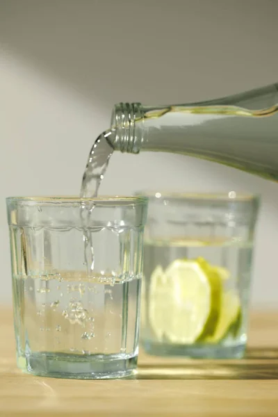 Vue rapprochée de verser de l'eau de la bouteille dans le verre — Photo de stock