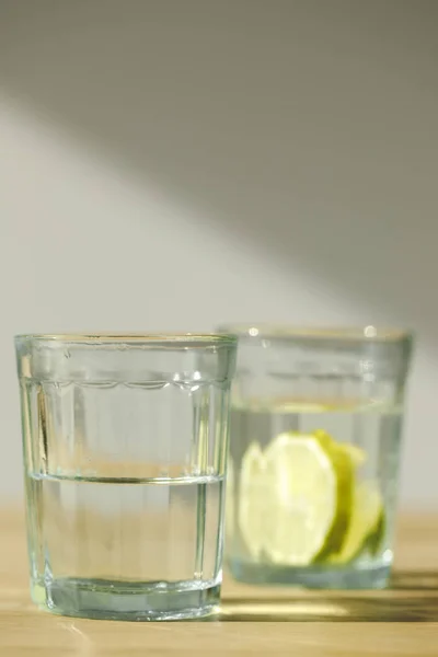 Primer plano vista de vidrio con agua y vidrio con limonada - foto de stock