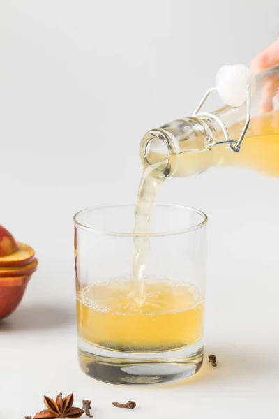 Tiro close-up de cidra refrescante derramando em vidro na superfície branca — Fotografia de Stock