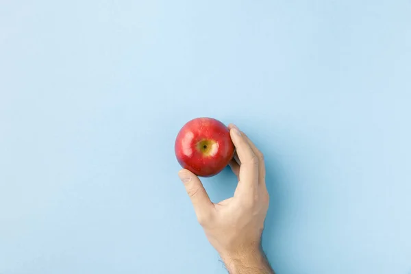 Vista superior de la mano sosteniendo manzana aislada en azul - foto de stock