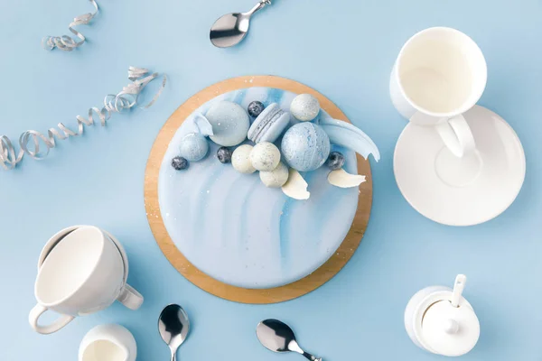 Vue du dessus du gâteau bleu avec des tasses, une assiette et des cuillères isolées sur bleu — Photo de stock