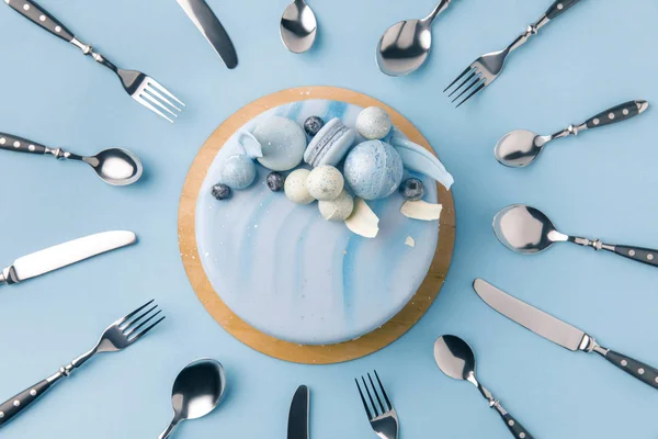 Vue de dessus du gâteau bleu entouré de couverts isolés sur bleu — Photo de stock