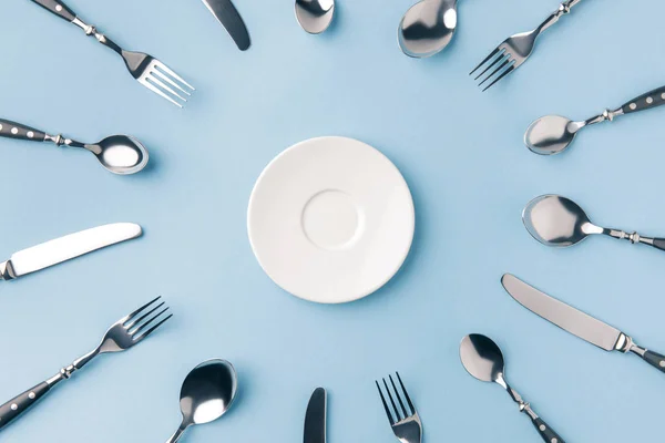 Top view of plate surrounded by flatware isolated on blue — Stock Photo
