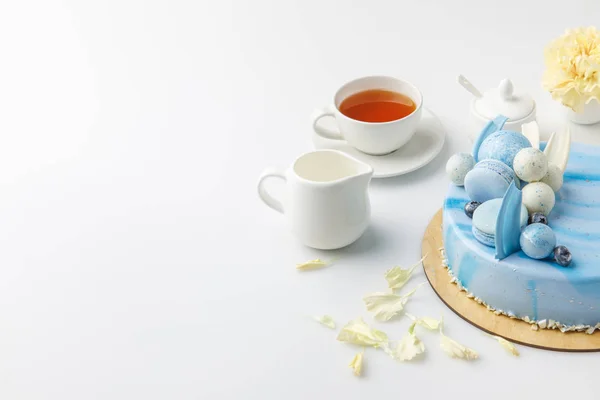 Blue tasty cake on chopping board with cup of tea isolated on white — Stock Photo