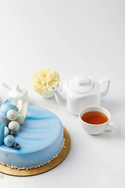 Gâteau savoureux bleu sur planche à découper avec thé et fleur isolé sur blanc — Photo de stock