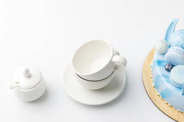 Pastel sabroso azul en la tabla de cortar con tazas de té aisladas en blanco - foto de stock