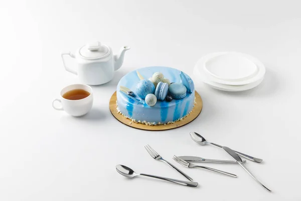 Blue tasty cake on chopping board with tea and plates isolated on white — Stock Photo