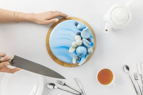 Draufsicht der abgeschnittenen Hände beim Aufschneiden von Kuchen auf Schneidebrett isoliert auf Weiß — Stockfoto