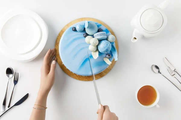 Draufsicht der abgeschnittenen Hände beim Aufschneiden von Kuchen auf Schneidebrett isoliert auf Weiß — Stockfoto