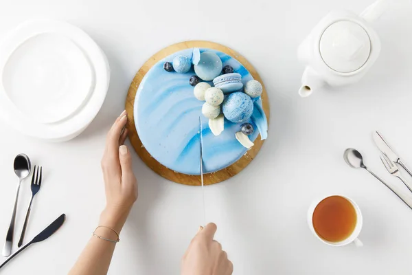 Draufsicht der abgeschnittenen Hände beim Aufschneiden von Kuchen auf Schneidebrett isoliert auf Weiß — Stockfoto