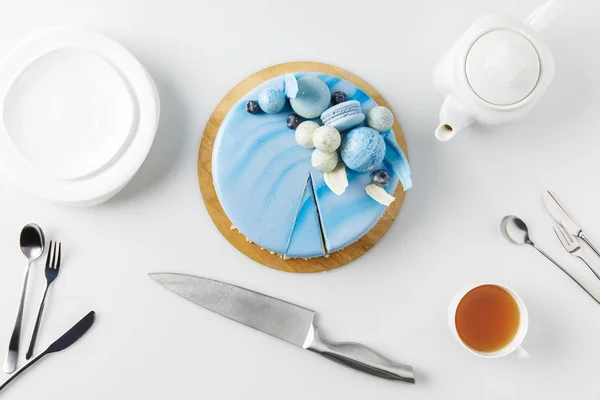 Top view of cake on chopping board with knife, plates and tea isolated on white — Stock Photo