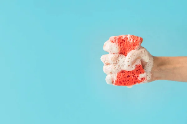 Cropped view of hand holding washing sponge with foam, isolated on blue — Stock Photo