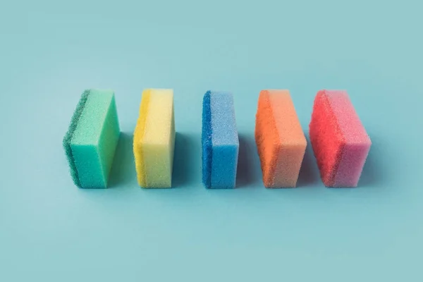 Ligne d'éponges colorées de cuisine de lavage, sur bleu — Photo de stock