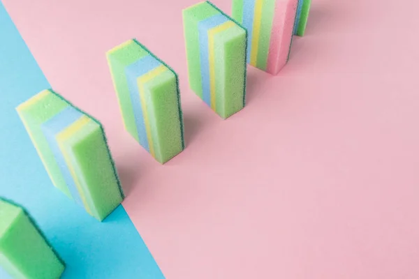 Line of colorful washing kitchen sponges, on blue and pink — Stock Photo
