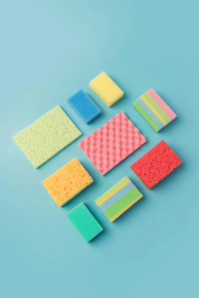 Vista superior de esponjas de lavagem coloridas, isoladas em azul — Fotografia de Stock