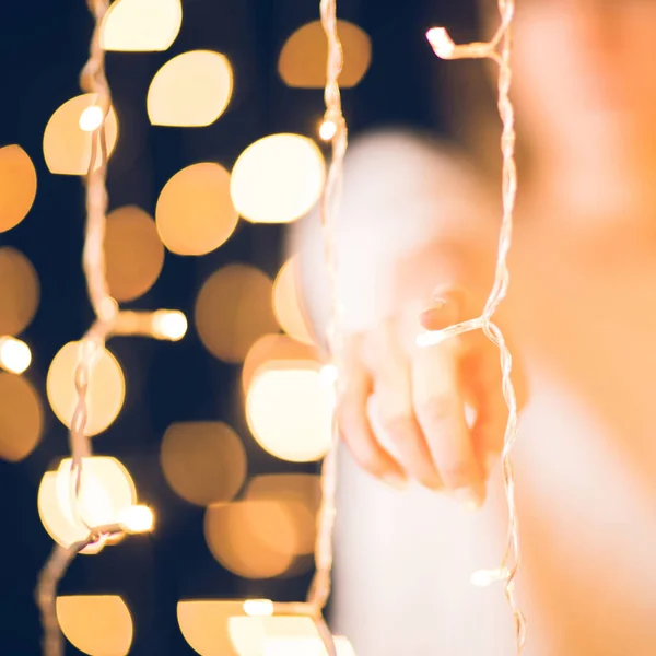 Cropped shot of woman pointing at camera behind holiday garland — Stock Photo