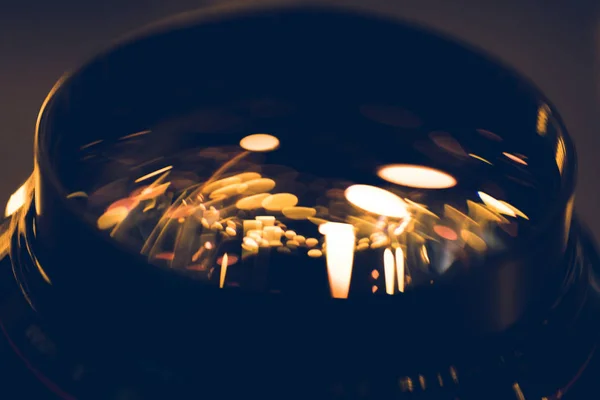 Gros plan des lumières dorées réfléchissant dans le verre de la lentille — Photo de stock