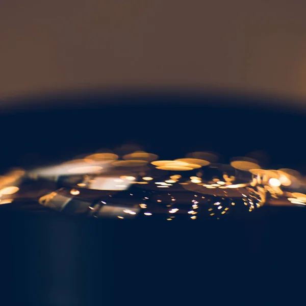 Primer plano de las luces doradas reflejadas en el cristal de la lente de la cámara - foto de stock