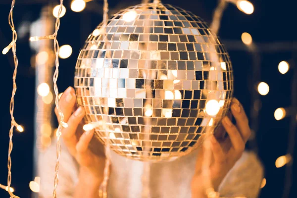 Femme touchant boule disco avec de belles guirlandes autour — Photo de stock