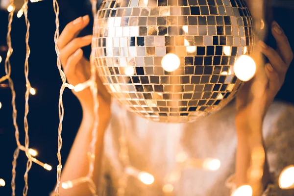 Close-up shot of woman touching disco ball with beautiful garlands around — Stock Photo