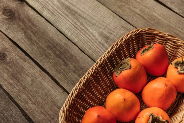 Overhead view of yummy ripe persimmons in straw basket — Stock Photo