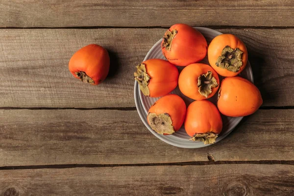 Top view of plates with orange persimmons on table — Stock Photo