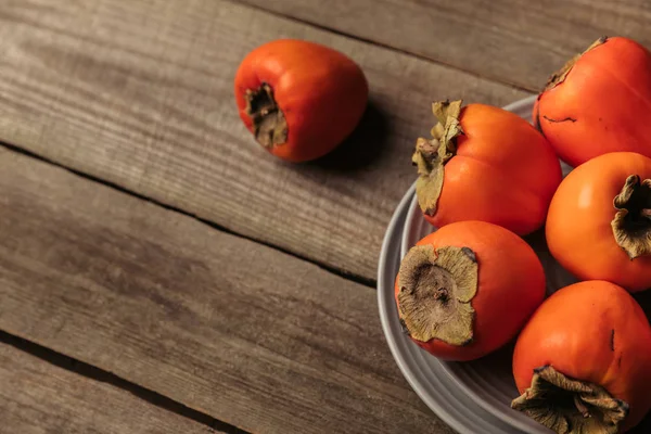 Ripe orange persimmons on gray wooden table — Stock Photo