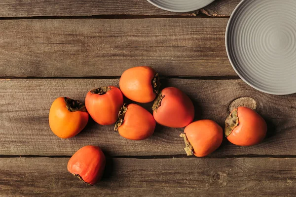 Vue de dessus des kaki mûrs éparpillés sur la table grungy — Photo de stock