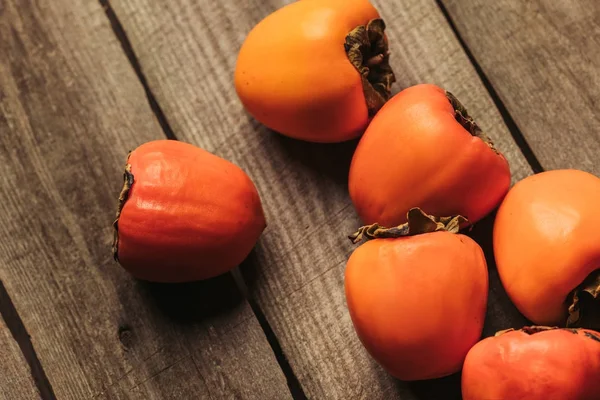 Scattered ripe persimmons on wooden gray surface — Stock Photo